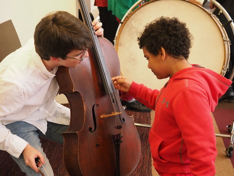 A little boy plucks a string on a cello.