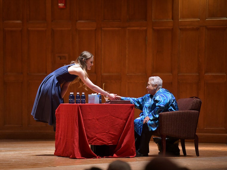 A woman shakes a student's hand, on stage.
