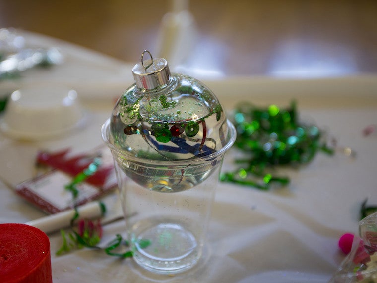 A clear ornament filled with confetti and water sits atop a plastic cup.