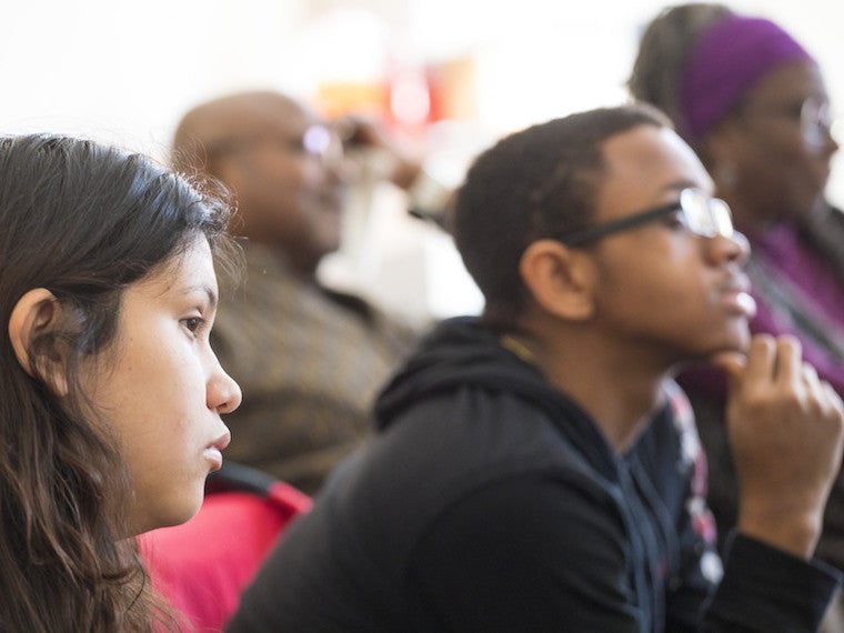 Students lean in and listen to a speaker.