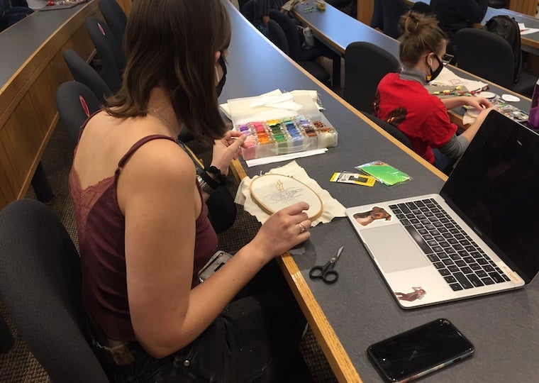 A girl looks at a needlepoint project in class.