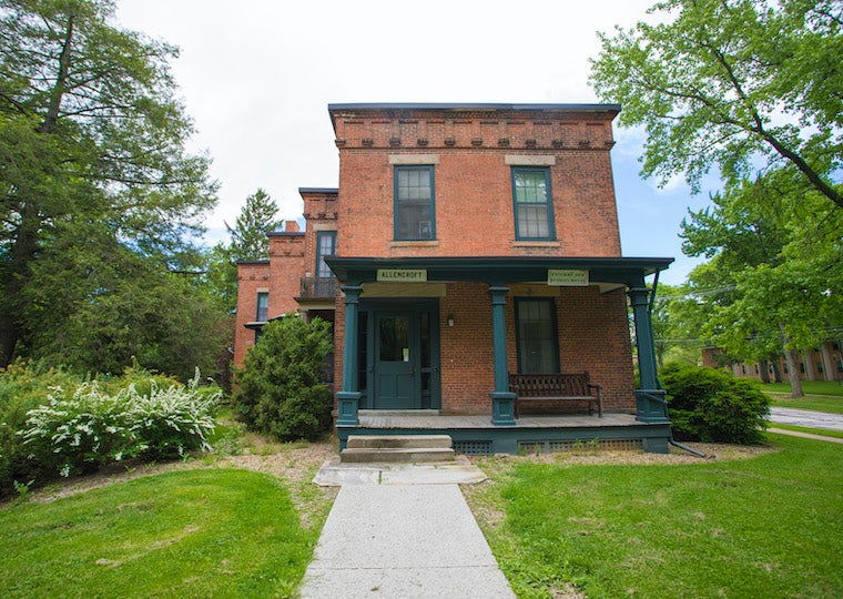 A square brick home with wooden porch and swing.