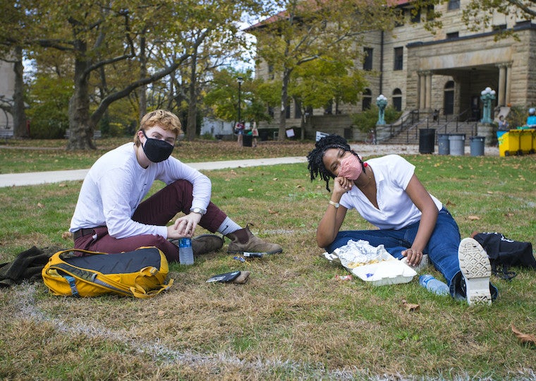 Two students sitting on the grass.