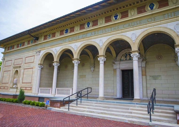 A stone brick ornate building with arched openings and stone steps.