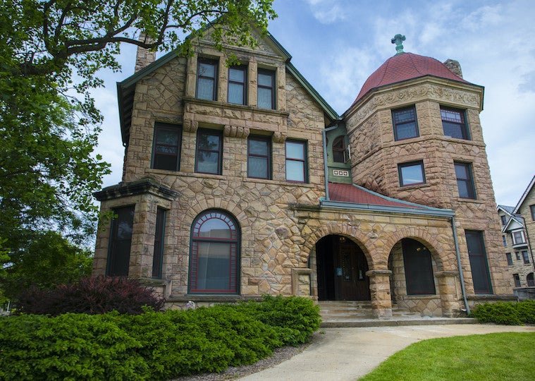 A brick home with a brick porch and rounded column on the side.