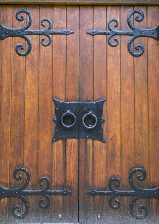 Double wooden heavy doors with round metal handles.