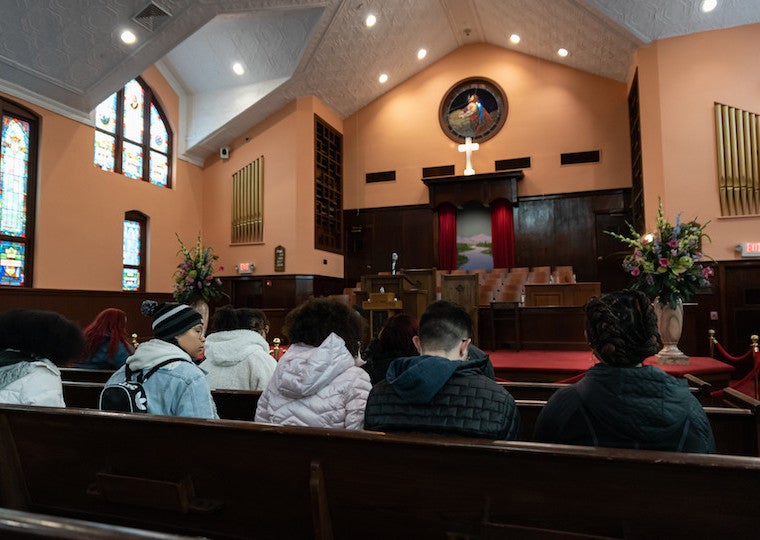 Students sit on pews inside a large church.
