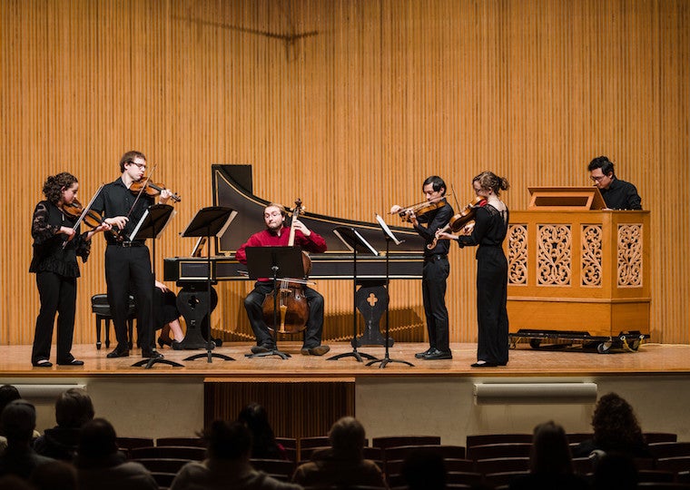 A group of conservatory students perform with instruments.