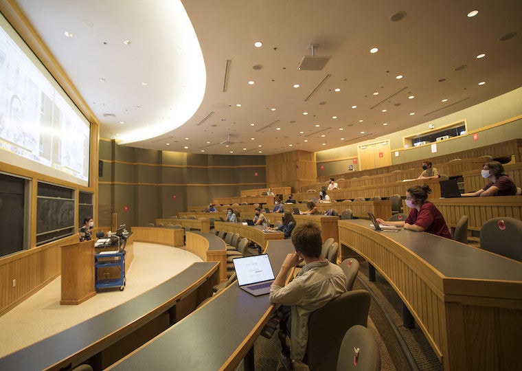 A lecture hall with students listening to a teacher.