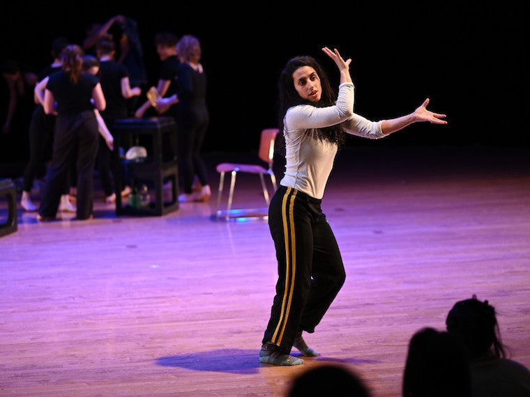 A woman dances in front of an audience.
