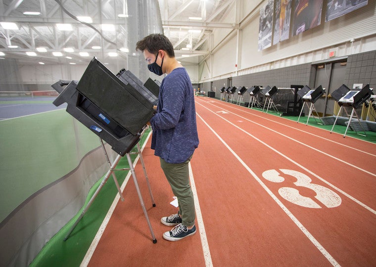 A student votes at a voting booth.