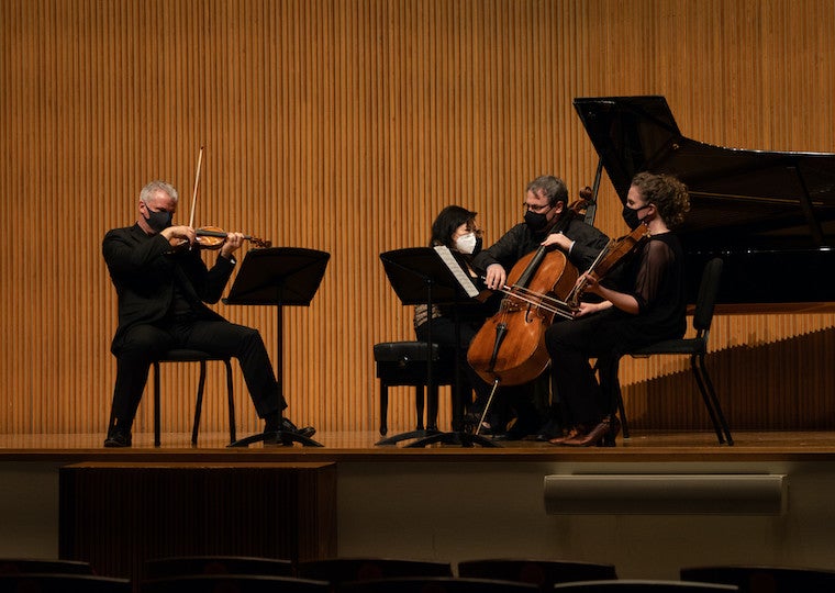 Faculty play violins during a recital.