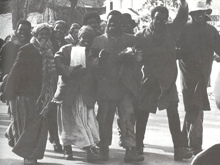 Nine students walk down the middle of a street.
