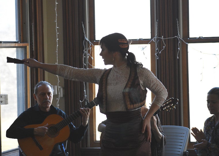 A woman holds a fan with her arm out stretched.