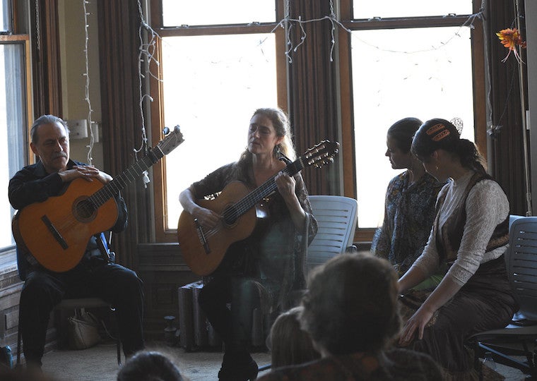 A group of musicians and twoLatin dancers sit in a semi-circle. 