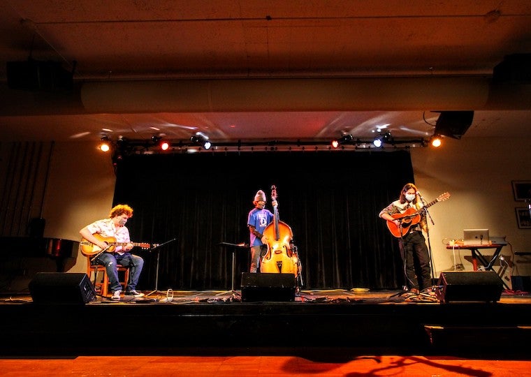 Three students perform jazz music on a stage.