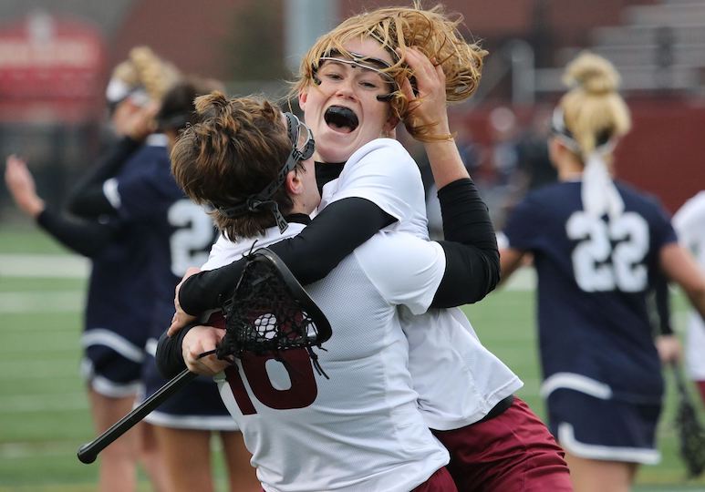 A girl lacrosse player jumps in the arms of her teammate