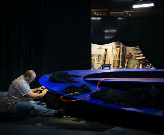 A man builds a round floor for a theater production