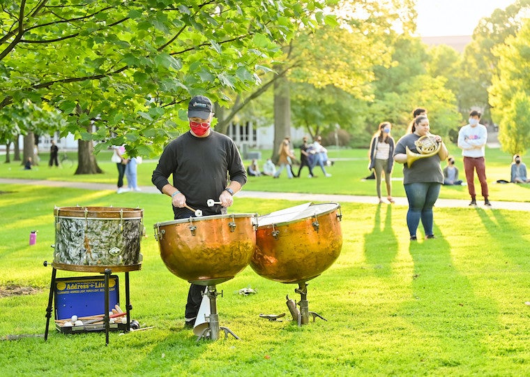 A student plays steel drums in a park.