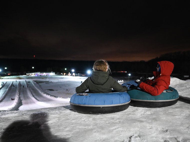 Two people sit in a snow tube