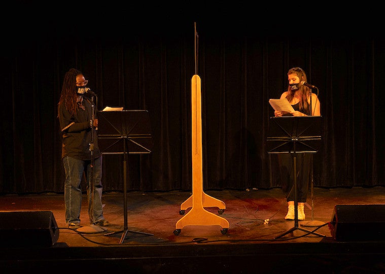 Two students give a reading on stage.