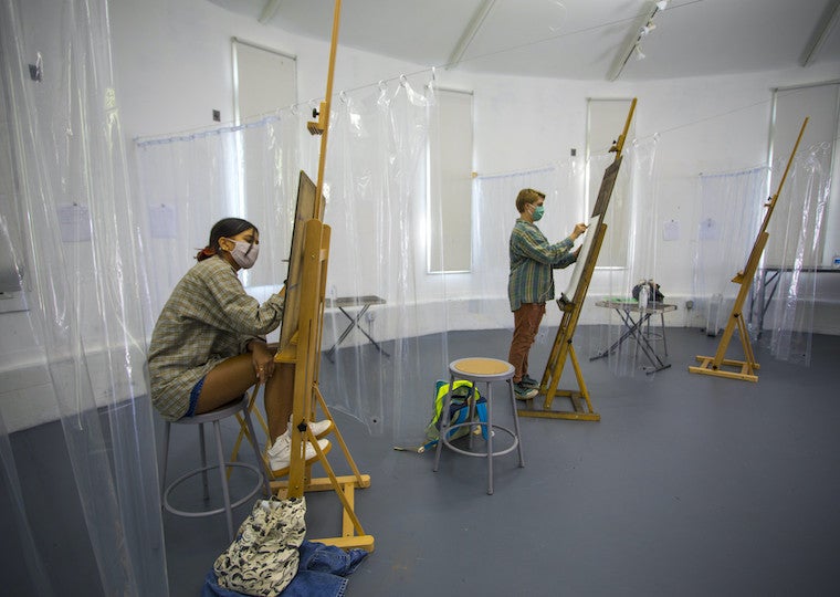 Two art student draw on large wooden easels.