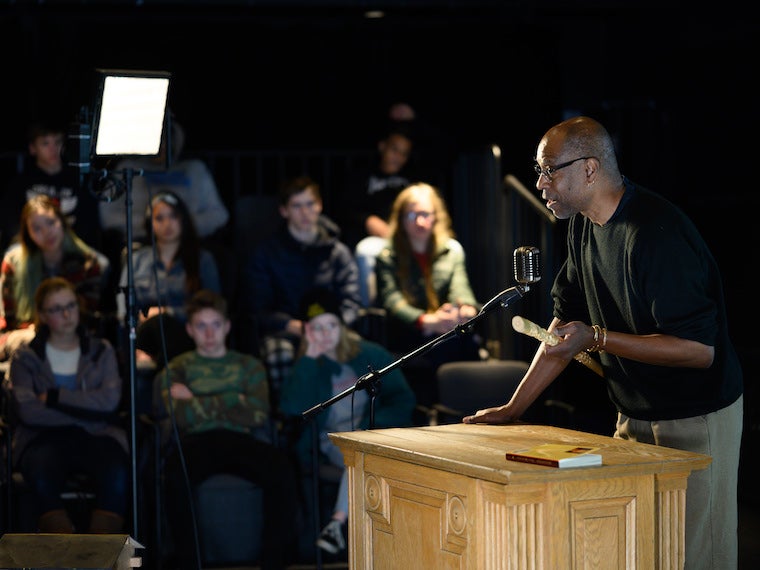 A man talks into a microphone at a podium.