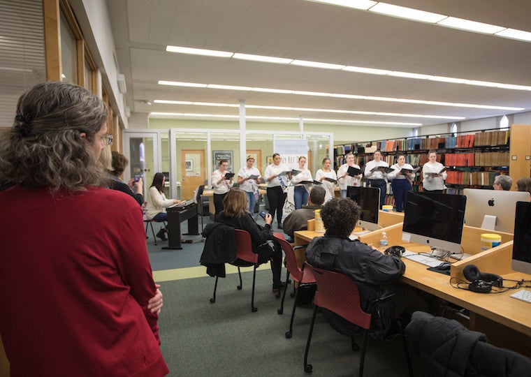 People in a library listen to a group singing.