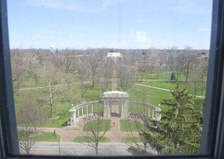 A window that looks out to a large stone monument in a park.