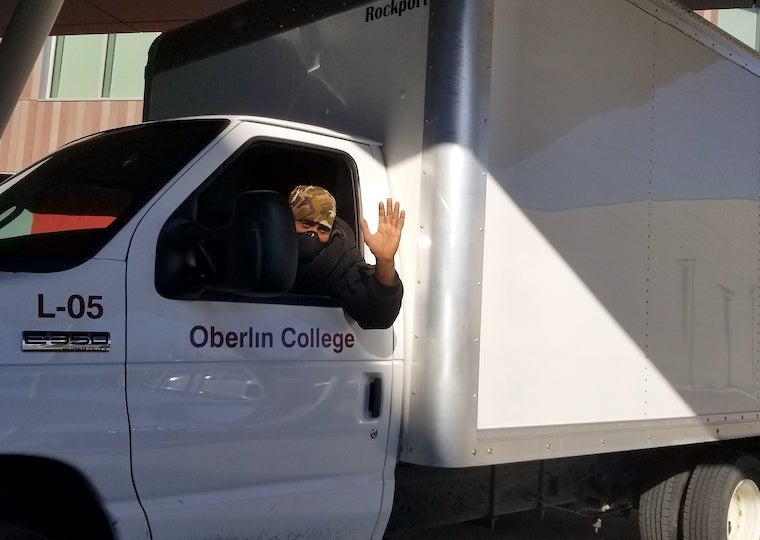 A man in a truck drives away while waving.