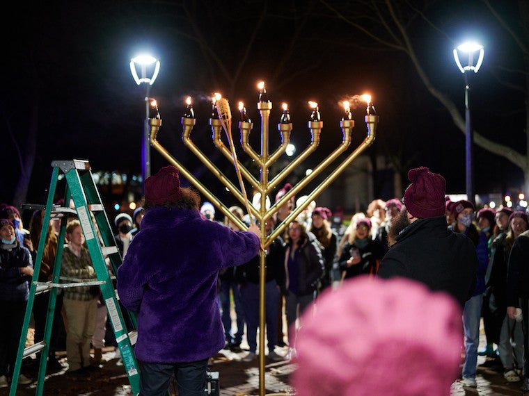 A small gathering of people attend a menorah lighting.