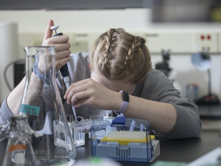 A student uses a pipette to place liquid into a rig.