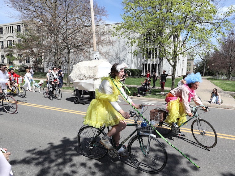 Students ride bikes while dressed in costumes.