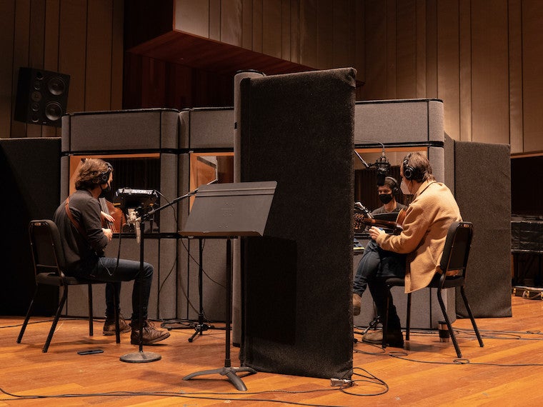 A recording studio with three people in it.