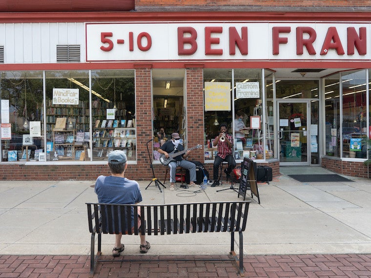 A small jazz band plays in front of a drugstore.