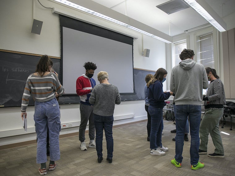 Students in a class stand in the middle of the room. 