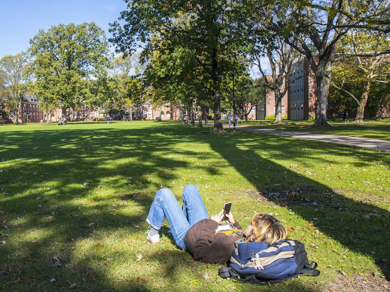 A student lays in the grass.