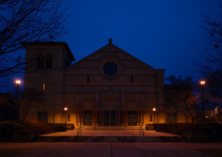The front of a large brick building at night.