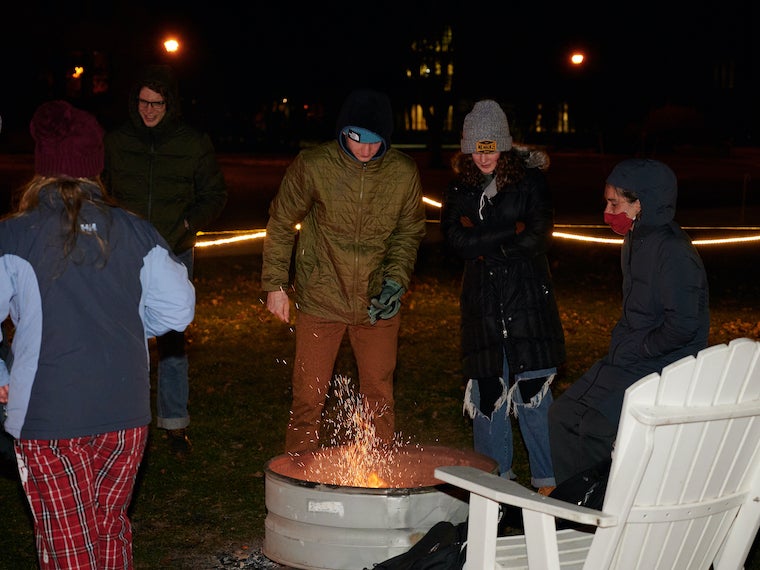 People stand around a fire pit.