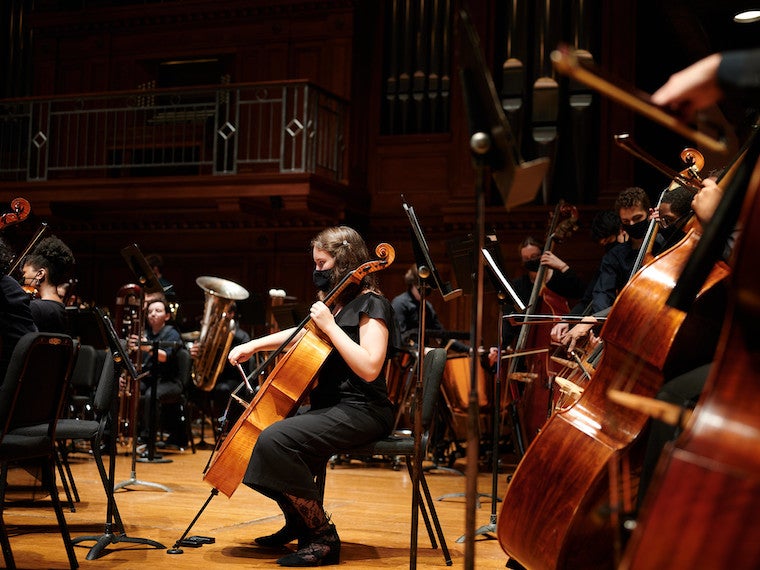 A girl playing the cello at a concert.