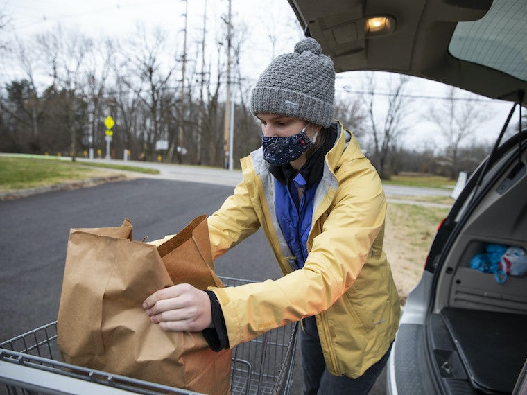 A college student loads groceries into a car.