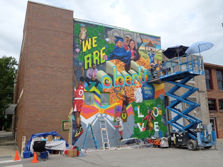 A tall lift next to a mural in a parking lot.