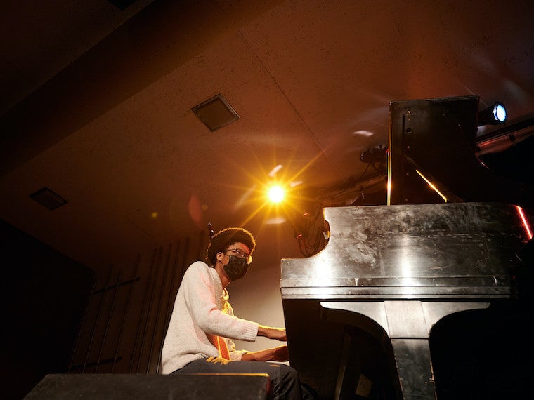 A student plays the piano on a stage.