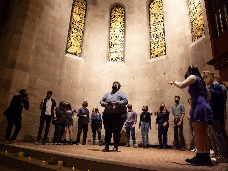 A group of students sing on a small stage.