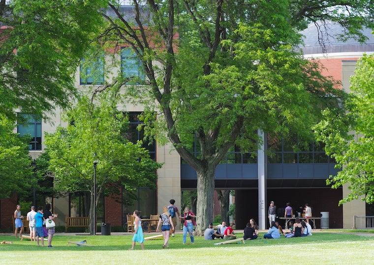 A group of students play games on a large lawn.