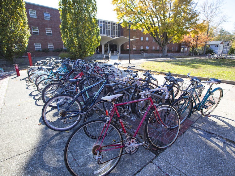 A long row of bikes parked in front of a dorm.