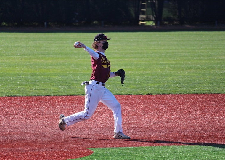 A male baseball player throws a ball in a game.