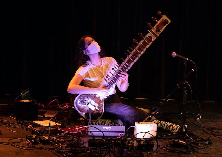 A woman plays an instrument on a stage.