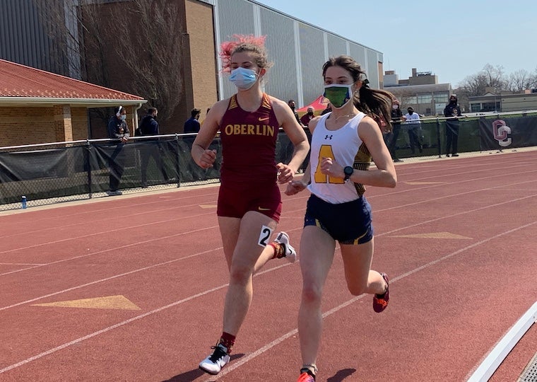 Two female college students race in a track meet.