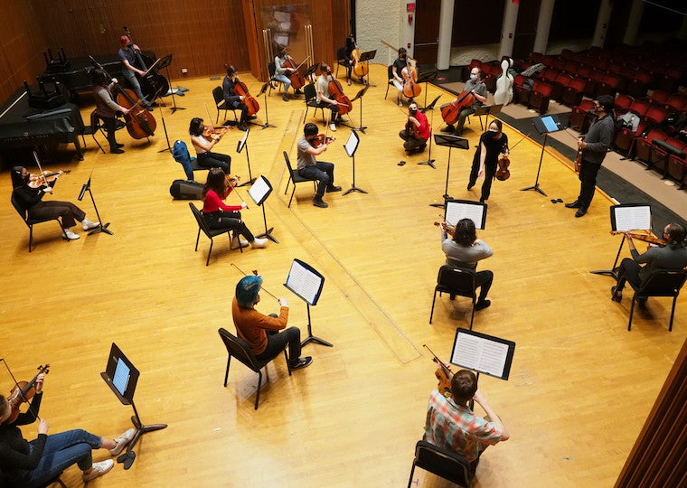 An overview picture of an orchestra practicing on a large stage.